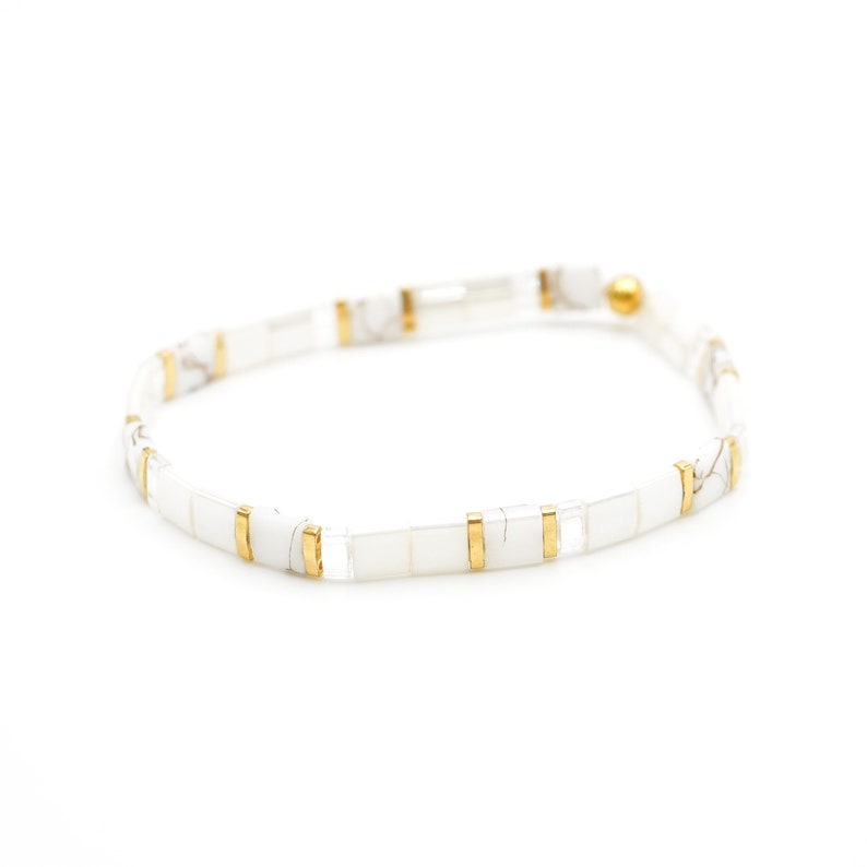 a white and gold bracelet on a white background