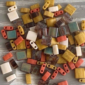 May include: Assortment of colorful ceramic tiles in various shapes and sizes. The tiles feature a mix of brown, beige, orange, and green hues. Some tiles have a speckled or marbled pattern.