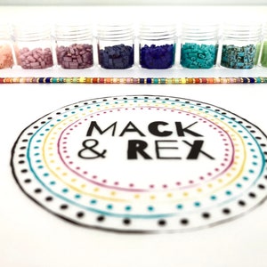 image of multiple colored beads in different plastic of beads, a bracelet, and the wipeable bead mat on a white background. 








Wipeable Bead Mat with Built-in Measuring Tape | Non-Slip Jewelry Making Tool | Perfect Beading Mat for DIY Projects