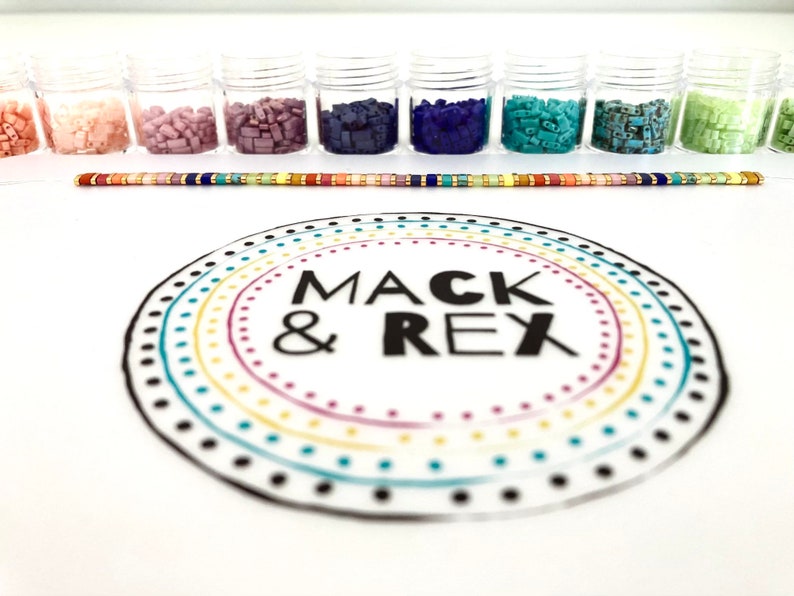 image of multiple colored beads in different plastic of beads, a bracelet, and the wipeable bead mat on a white background. 








Wipeable Bead Mat with Built-in Measuring Tape | Non-Slip Jewelry Making Tool | Perfect Beading Mat for DIY Projects