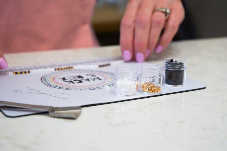 image of a person measuring the length of a bracelet with the in-built measuring tape of the wipeable bead mat. 






Wipeable Bead Mat with Built-in Measuring Tape | Non-Slip Jewelry Making Tool | Perfect Beading Mat for DIY Projects