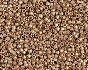 May include: A close-up shot of a pile of small, cylindrical beads. The beads are a metallic gold color and have a hole running through the center. These beads are likely used for jewelry making or other craft projects.