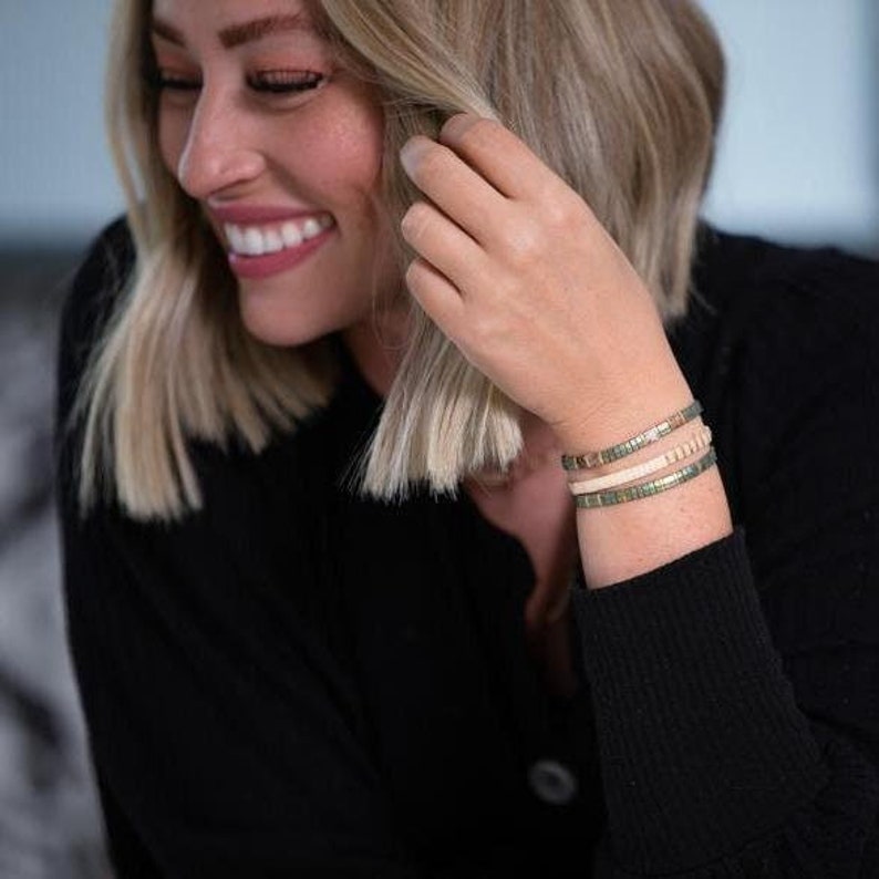 a woman smiles as she adjusts her bracelet