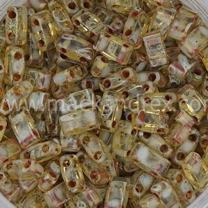 May include: A pile of rectangular, transparent beads with a yellow-gold hue. Each bead has two holes and internal red and white accents. The website address "www.maekondrex.com" is visible in the lower left corner.