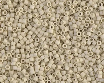 May include: A close-up shot of a pile of small, off-white, cylindrical beads. Each bead has a hole running through the center. The beads are scattered, creating a textured surface. These beads are suitable for jewelry making and crafts.