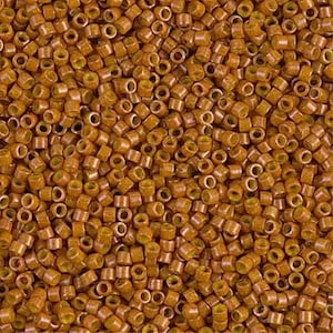 May include: A close-up view of a pile of small, cylindrical beads. The beads are a warm, golden-brown color with a slightly translucent appearance. The beads are densely packed together, filling the frame.