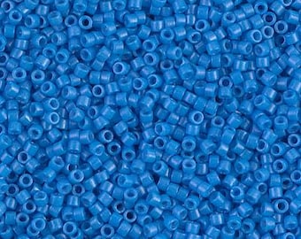 May include: A close-up shot of a pile of small, cylindrical, blue beads. Each bead has a hole running through the center. The beads are scattered, creating a textured surface.
