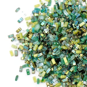 May include: A large pile of green, blue, and yellow glass seed beads. The beads are all rectangular in shape and have a slightly iridescent finish.