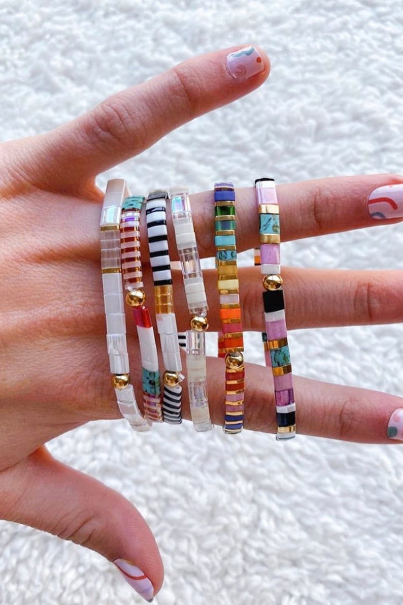 a woman's hand with a bunch of bracelets on it