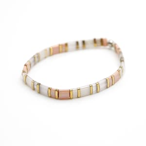 a white and gold bracelet on a white background