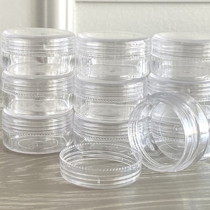 May include: A stack of clear plastic containers with lids. The containers are stacked in a pyramid shape. The containers are all the same size and shape.