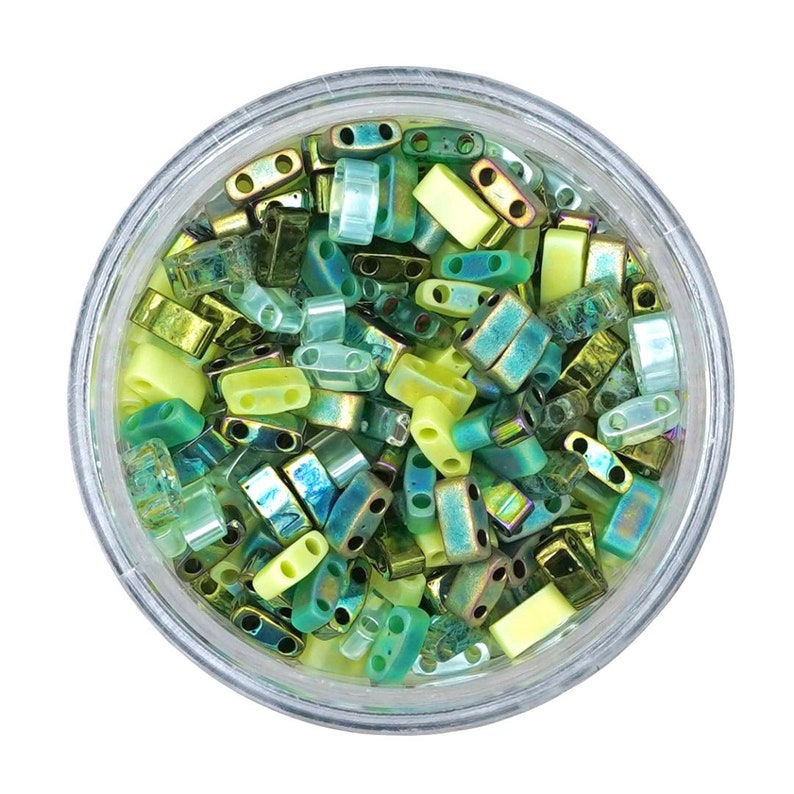 May include: A clear plastic container filled with a mix of green and yellow glass seed beads. The beads are various shapes and sizes, including squares, rectangles, and ovals.