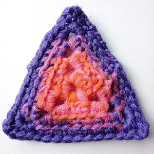 May include: A purple, pink, and orange crocheted triangle.