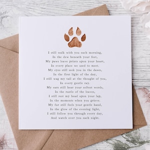 May include: A white card with a brown paw print and a poem about a pet that has passed away. The poem reads, "I still walk with you each morning, In the dew beneath your feet, My paws leave prints upon your heart, In every place we used to meet. My eyes still seek you in the dawn, In the first light of the day, I still wag my tail at the thought of you, In every gentle ray. My ears still hear your softest words, In the rustle of the leaves, I still rest my head upon your lap, In the moments when you grieve. My fur still feels your gentle hand, In the glow of the evening light, I still follow you through every day, And watch over you each night."