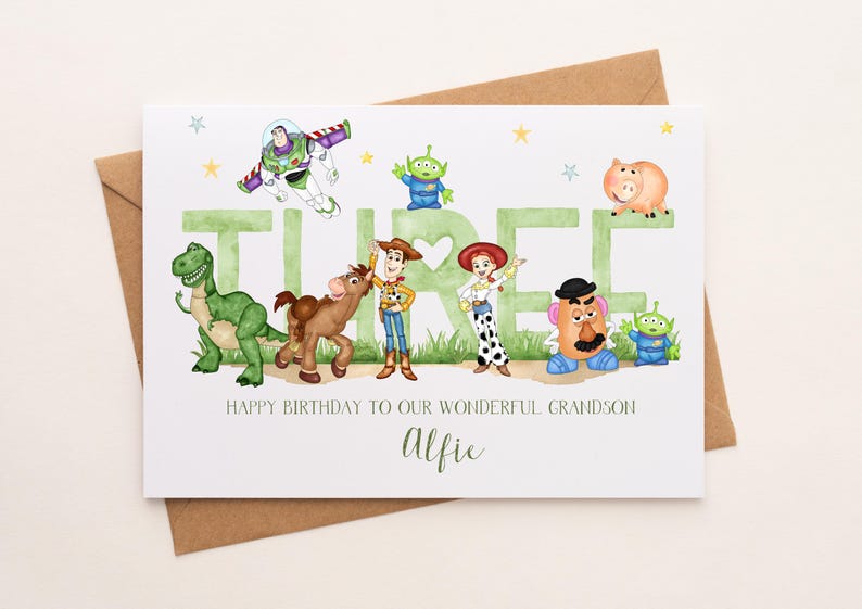 May include: A white birthday greeting card featuring watercolor illustrations of Toy Story characters including Buzz Lightyear, Woody, Jessie, Rex, Bullseye, Mr. Potato Head, and aliens. The word THREE is printed in green with the text Alfie below.