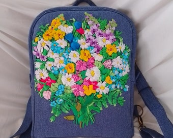 Mochila vaquera azul hecha a mano con cintas bordadas y un ramo de