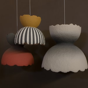 May include: Three hanging paper lampshades. The top lampshade is yellow, the middle lampshade is black and white striped, and the bottom lampshade is red.