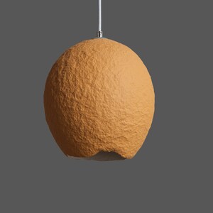 K&ouml;nnte beinhalten: Eine runde, orangefarbene, strukturierte Pendelleuchte mit einem wei&szlig;en Kabel.