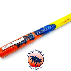 May include: A colorful pen with a vibrant design. The pen features a bright orange, blue, and yellow pattern. It has a silver clip and the text "Prestige" is visible. The pen is a writing instrument.