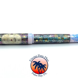 Puede incluir: Un bol&iacute;grafo &uacute;nico con un dise&ntilde;o steampunk. El bol&iacute;grafo presenta un dise&ntilde;o de esfera de reloj en el cuerpo, con engranajes y un extremo veteado azul y blanco. Es un instrumento de escritura.