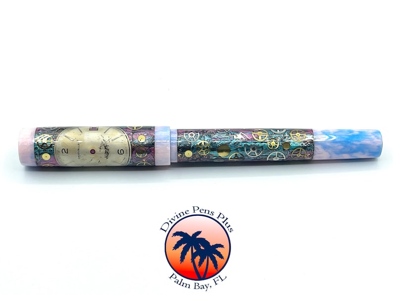 Puede incluir: Un bol&iacute;grafo &uacute;nico con un dise&ntilde;o steampunk. El bol&iacute;grafo presenta un dise&ntilde;o de esfera de reloj en el cuerpo, con engranajes y un extremo veteado azul y blanco. Es un instrumento de escritura.