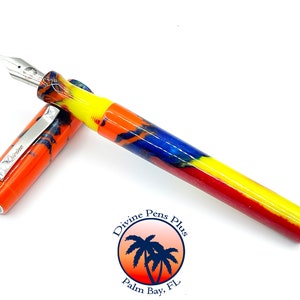 May include: A colorful fountain pen with a silver nib and clip. The pen's body features a vibrant pattern of orange, yellow, blue, and red. The clip is engraved with the word "Divine". The pen is from Divine Pens Plus, Palm Bay, FL.