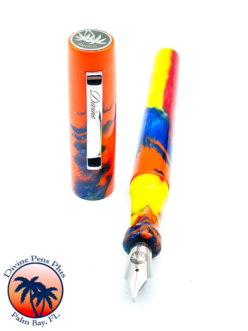 May include: A colorful fountain pen with an orange cap and a marbled barrel in shades of yellow, blue, and orange. The cap is off, revealing the nib. The pen is labeled "Divine" and the logo of "Divine Pens Plus Palm Bay, FL" is in the lower left.