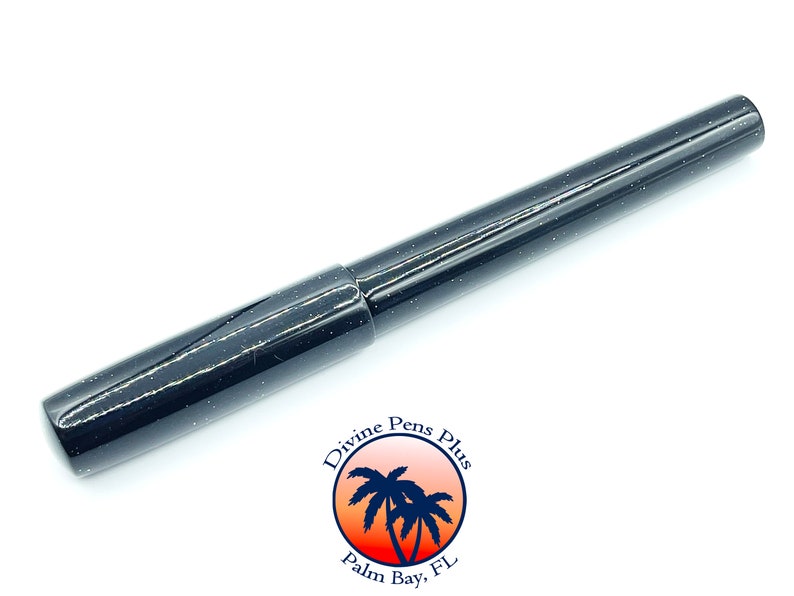 May include: A black pen with a speckled design. The pen has a cap and a cylindrical body. The pen is from Divine Pens Plus, Palm Bay, FL.