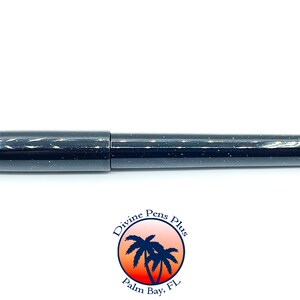 May include: A black pen with a speckled design. The pen has a cap and a cylindrical body. The pen is from Divine Pens Plus, Palm Bay, FL, as indicated by the logo at the bottom of the image.