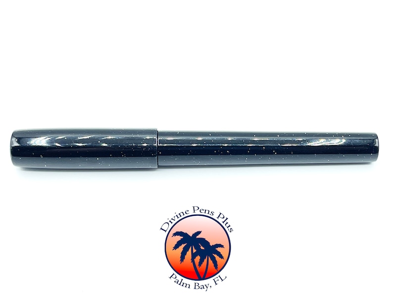 May include: A black pen with a speckled design. The pen has a cap and a cylindrical body. The pen is from Divine Pens Plus, Palm Bay, FL, as indicated by the logo at the bottom of the image.