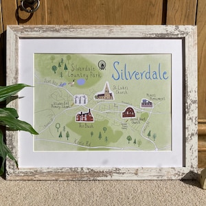 May include: A hand-drawn map of Silverdale, a town in England, with a green background and blue text. The map shows the location of various landmarks, including Silverdale Country Park, St. Luke's Church, and the Sacred Heart Church.