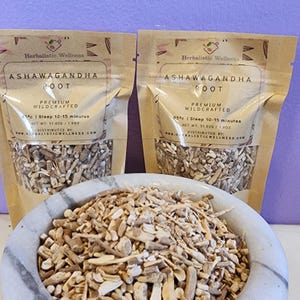 May include: Two brown paper pouches of dried ashwagandha root, labeled "Ashwagandha Root" with the text "Premium Wildcrafted" and "85&deg;c | Steep 10-15 minutes". A white ceramic mortar and pestle is filled with the dried root.
