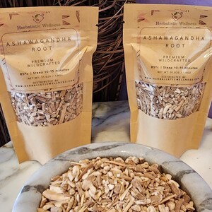 May include: Two brown paper bags filled with dried ashwagandha root. The bags have a white label with the text "Herbalistic Wellness Ashwagandha Root Premium Wildcrafted 85&deg;c | Steep 10-15 minutes Net Wt: 51.02g / 1.90z Distributed by Herbalistic Wellness.com". A white bowl filled with dried ashwagandha root is in the foreground.