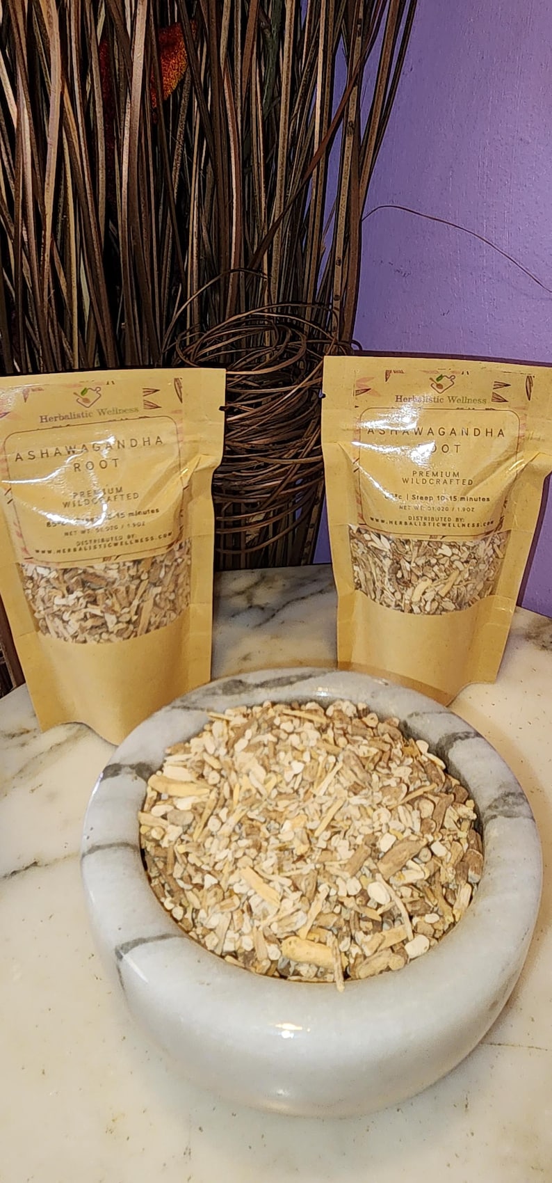 May include: Two brown paper pouches with white text that reads "Herbalistic Wellness Ashwagandha Root Premium Wildcrafted" and "Steep 10-15 minutes Net Wt 3.7 oz (105g)". A white ceramic bowl filled with light brown, dried root pieces.