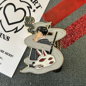 May include: Gold-tone enamel pin featuring a man in a suit with a wolf mask and smoke coming from his mouth. The pin is surrounded by a gray swirl.