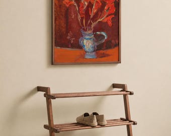 May include: A three-tiered wooden shoe rack with a dark brown finish, featuring horizontal slats. On the middle shelf sits a pair of beige slip-on shoes, while the bottom shelf holds a pair of dark brown leather dress shoes. Above hangs a framed painting.