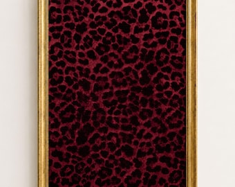 May include: A rectangular wall art piece featuring a deep burgundy and black leopard print pattern. The artwork is encased in a thin, textured gold-colored frame with a metallic finish, providing a clear contrast to the dark animal print design.