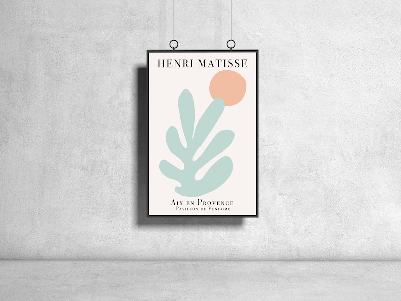 May include: A framed print of a minimalist art piece by Henri Matisse. The print features a light blue leaf shape with a peach-colored circle above it. The text "Aix en Provence, Pavillon de Vendome" is at the bottom of the print.