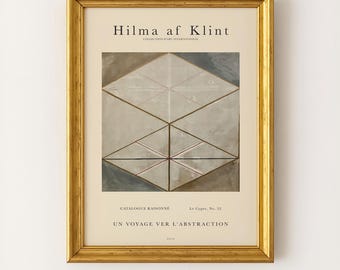 May include: A framed art print featuring the text Hilma af Klint, Collection d'Art International, Catalogue Raisonné, Le Cygne, No. 22, and Un Voyage Ver L'Abstraction. The central image displays a geometric composition of triangles in shades of gray, white, and brown, enclosed in a gold-toned frame.