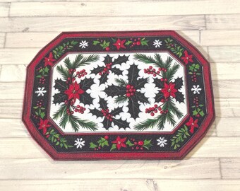 Könnte beinhalten: Ein rechteckiger Weihnachts-Teppich mit einem schwarzen und roten Rand. Die Mitte zeigt einen weißen Hintergrund mit einem Muster aus Stechpalmenblättern, roten Beeren und Weihnachtssternen. Grüne Tannennadeln und weiße Schneeflocken vervollständigen das festliche Design.