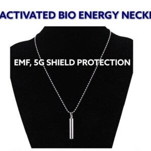 May include: A silver necklace with a small, cylindrical pendant. The necklace is on a black background and the text "CHI ACTIVATED BIO ENERGY NECKLACE" and "EMF, 5G SHIELD PROTECTION" is above and below the necklace.