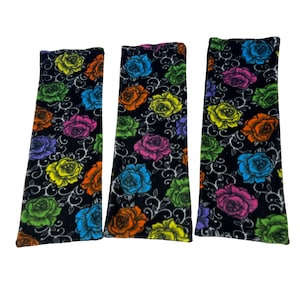 May include: Three black fabric rectangular pouches with a colorful floral pattern. The flowers are in shades of pink, yellow, orange, green, and blue.