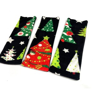 May include: Three Christmas-themed fabric items with a black background. The items feature various Christmas tree designs in green, red, and white, along with white stars. The items are likely decorative or functional, possibly for holiday use.