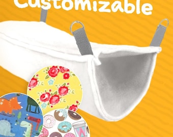 May include: White pet hammock with gray straps and the word "Customizable" in white. Includes three fabric swatches with floral, dinosaur, and donut patterns. The hammock is designed for small pets.