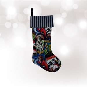May include: A Christmas stocking with a black and white striped cuff and a colorful print of classic horror movie monsters. The stocking features images of Frankenstein, Dracula, the Creature from the Black Lagoon, and the Wolfman. The text on the stocking includes "The Horror", "The Fright", and "Monsters".