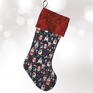 May include: A Christmas stocking with a red cuff and a loop for hanging. The body of the stocking is navy blue with a repeating pattern of snowmen, Santa, and Christmas trees. The stocking is made of fabric.