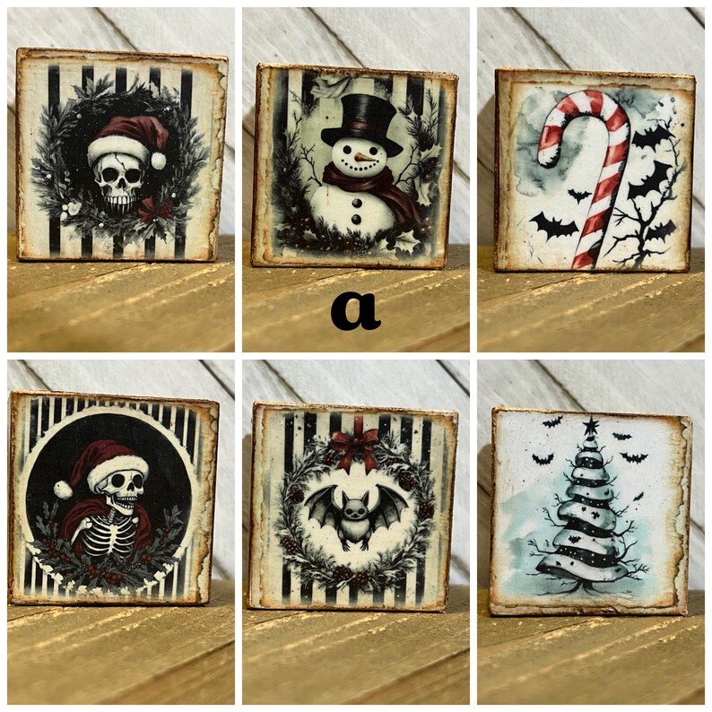 May include: Set of six square wooden blocks with different Christmas-themed illustrations. The blocks feature a skull wearing a Santa hat, a snowman, a candy cane, a bat in a wreath, a skeleton wearing a Santa hat, and a Christmas tree.