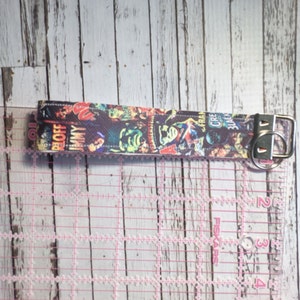 May include: A colorful key chain with a black background and a variety of comic book covers featuring characters like "The Blob", "Jimmy", "Creature from the Black Lagoon", and "The Creeper".