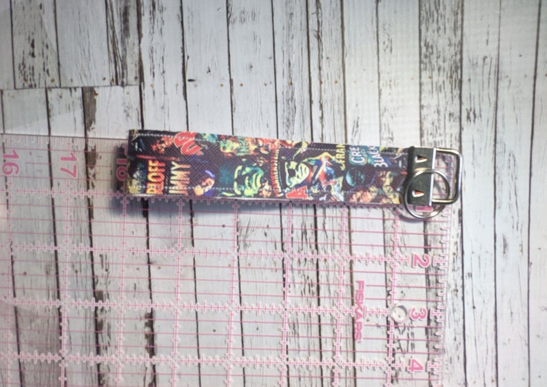 May include: A colorful key chain with a black background and a variety of comic book covers featuring characters like "The Blob", "Jimmy", "Creature from the Black Lagoon", and "The Creeper".