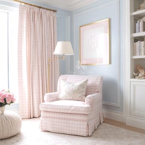 May include: A light pink and white gingham upholstered armchair with a pleated skirt, featuring a floral print throw pillow. The chair is positioned next to a brass floor lamp with a white shade and matching pink and white gingham curtains.